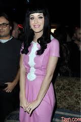  here is katy perry with a गुलाबी dress and curly hair.