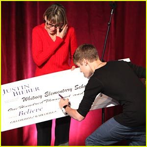  Justin Bieber signs his name on the dotted line in this new shot from his visit to Whitney Elementary School on Friday afternoon (December 16).
