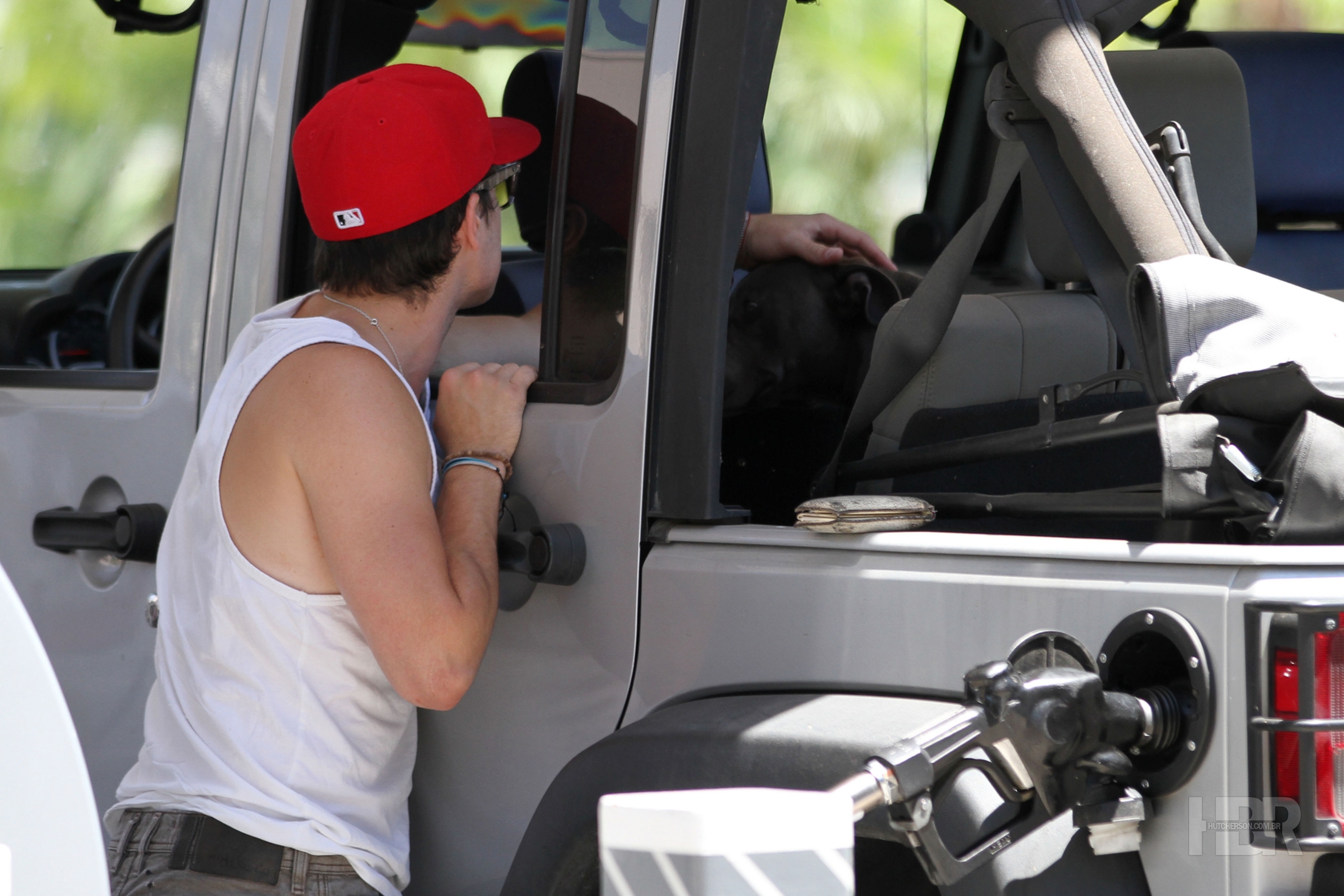 Josh puts gas in his car with his dog, Driver.